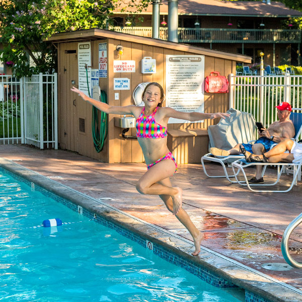 Smiling young girl jumping into the pool at Shallows Resort