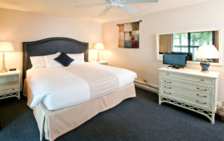 Beachhouse well lit bedroom with large bed and dressers