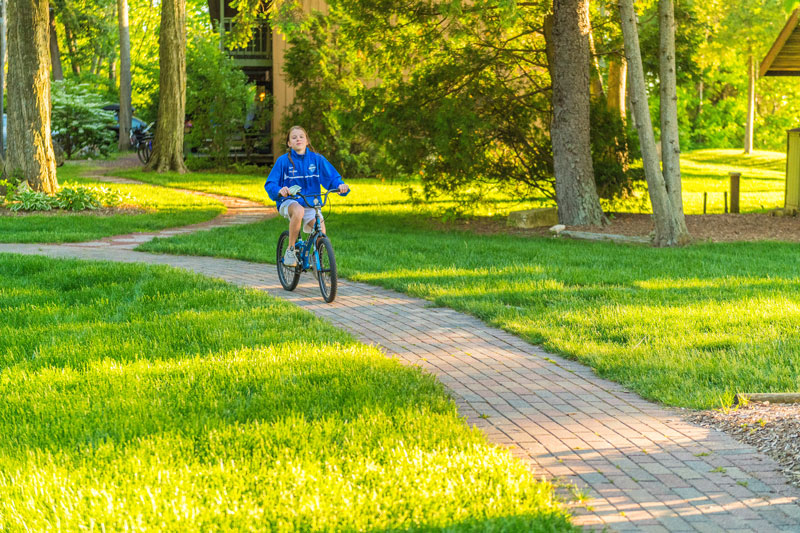 Small child riding bike on winding path on Shallows Resort property