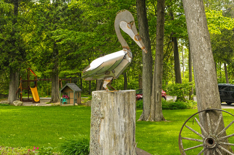 Metal pelican sculpture on wooden base