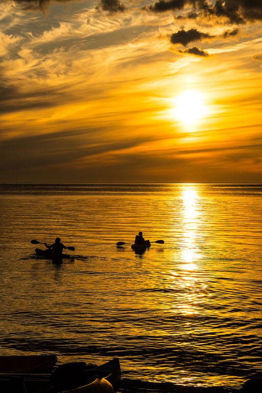 Two kayakers at sunset on the bay