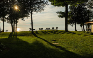 Line of lawn chairs along the shore with sunset over the water