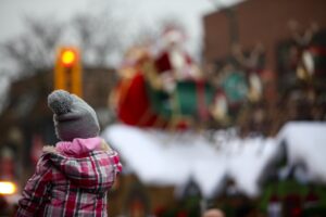 A young girl watching a Christmas parade float with Santa Clause