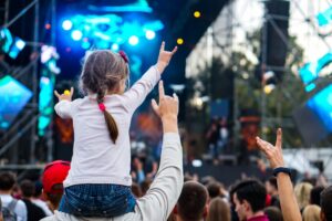 A young girl on her father's shoulders watching a street concert