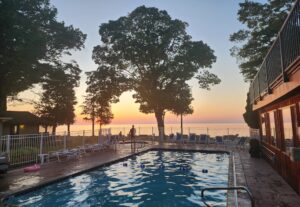 A vacation rental resort pool with lake views and a sunset in the background