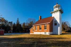 A historic white-brick lighthouse in the morning sun